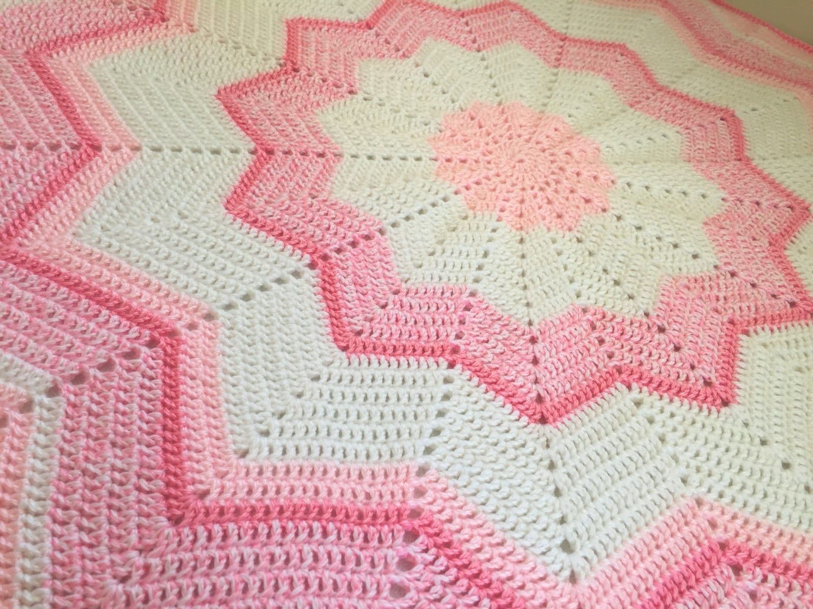 A round pink and white ripple crochet baby blanket