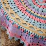 Crochet round tablecloth handmade in cream cotton with intricate lace pattern on a wooden dining table