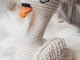 Handmade crochet swan toy with embroidered eyes and orange beak