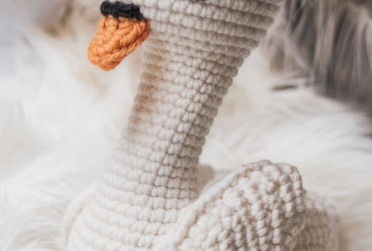 Handmade crochet swan toy with embroidered eyes and orange beak