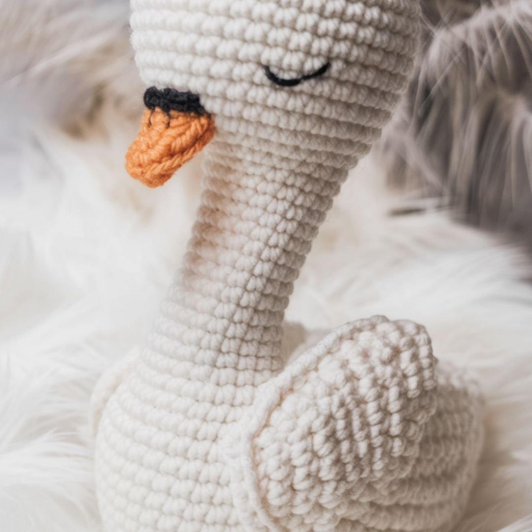Handmade crochet swan toy with embroidered eyes and orange beak